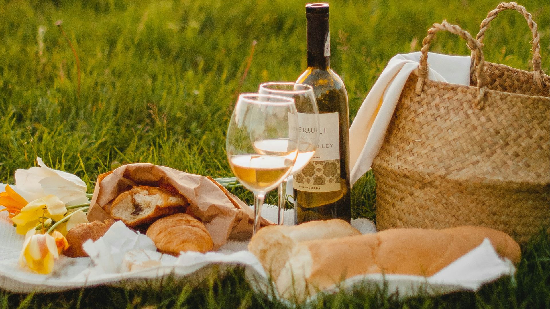 clear glass bottle beside brown wicker basket on green grass during daytime