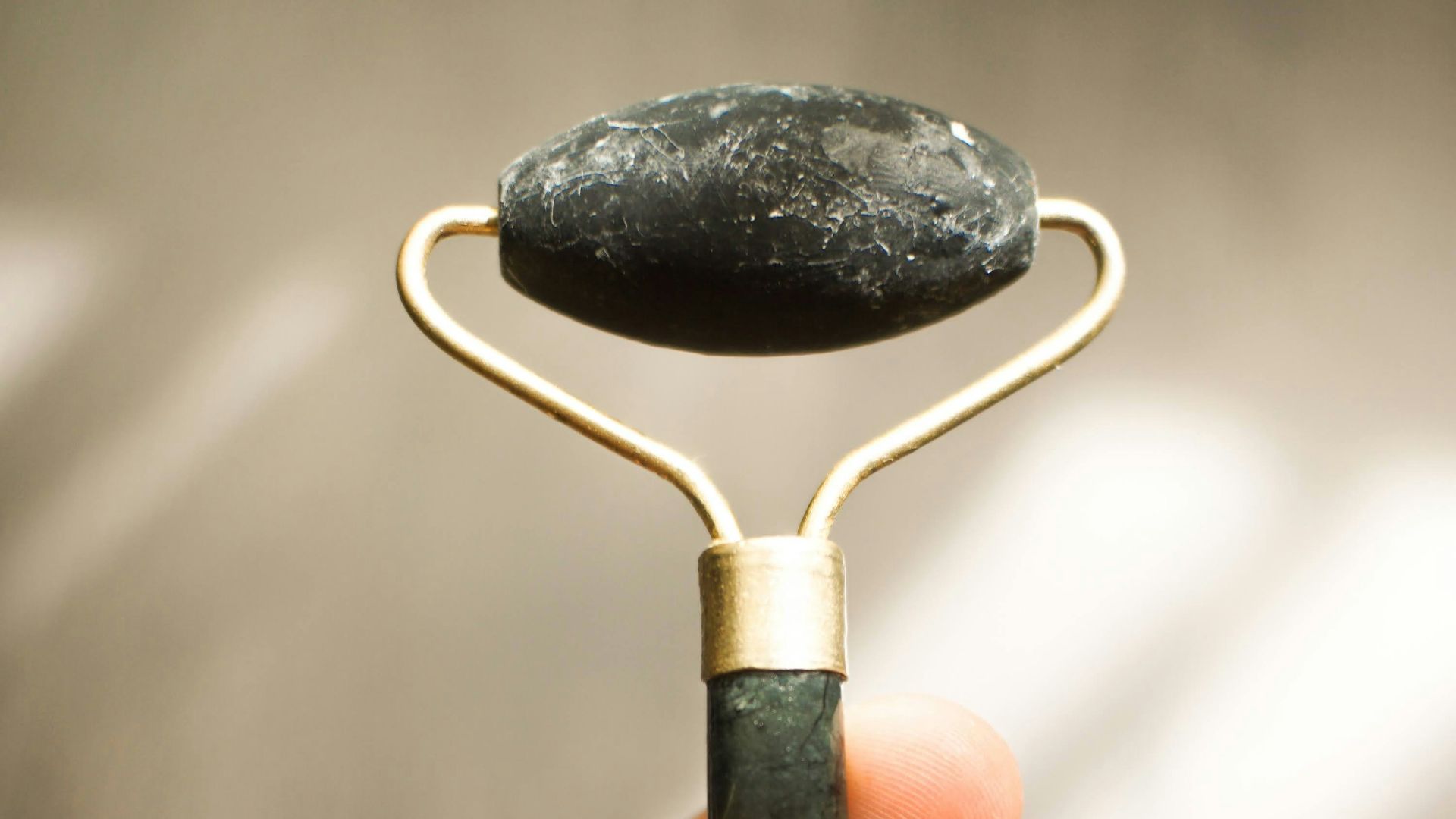 a hand holding a metal object with a rock on top of it