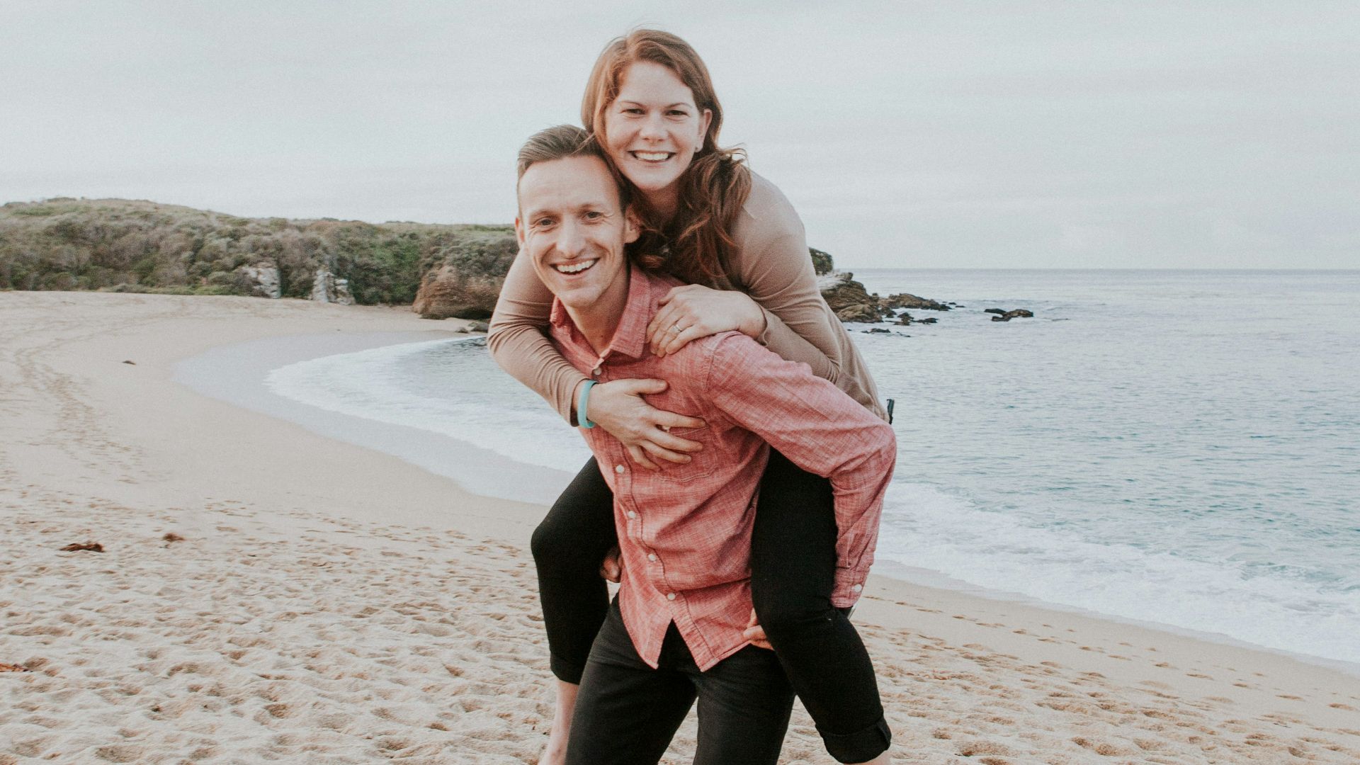 man carrying woman beside seashore