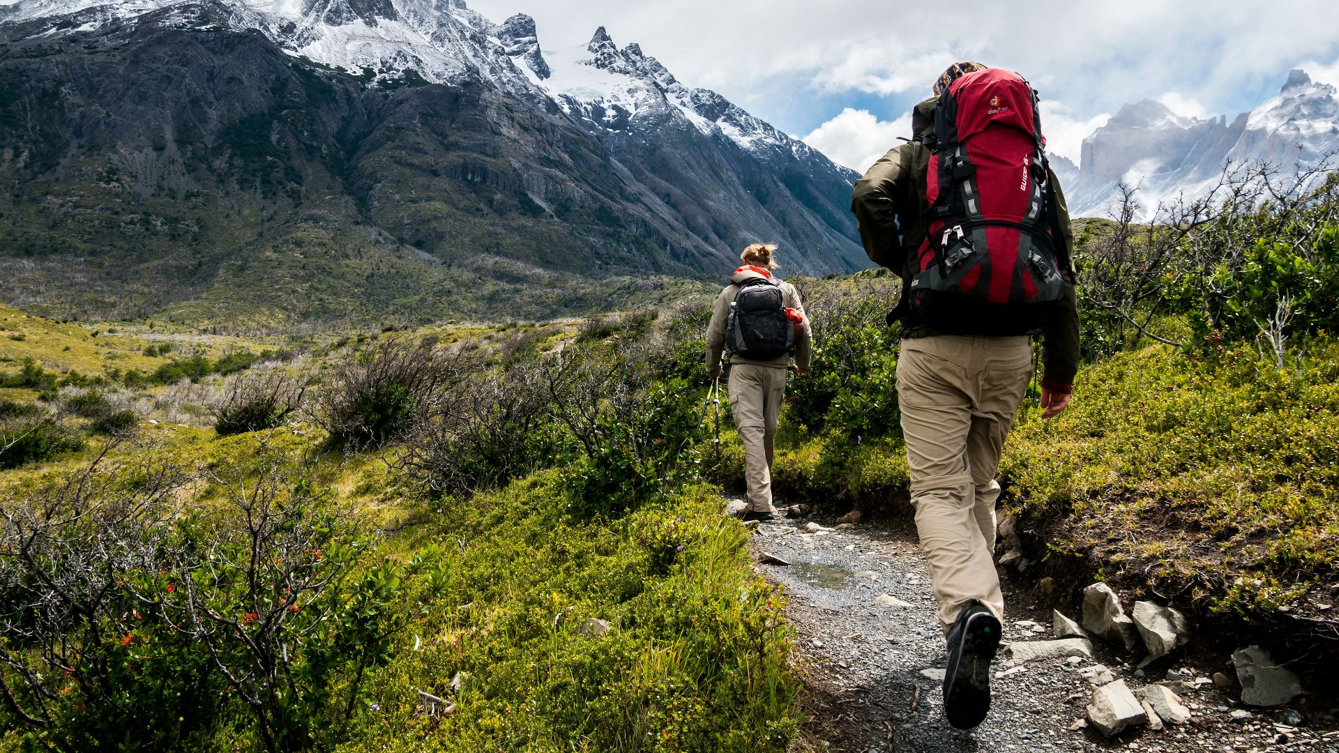 two person walking towards mountain covered with snow