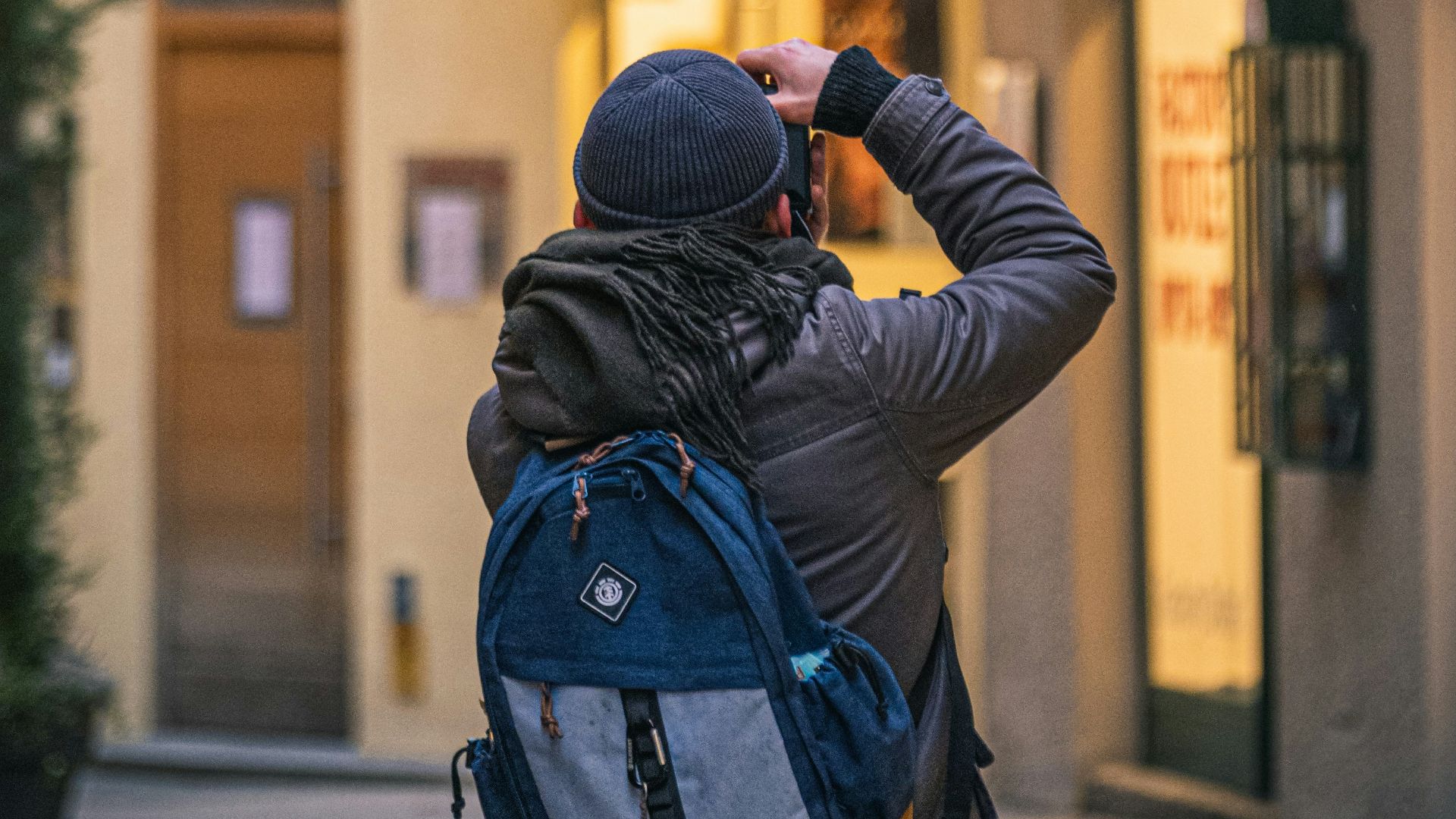 man in black jacket taking photo of store during daytime