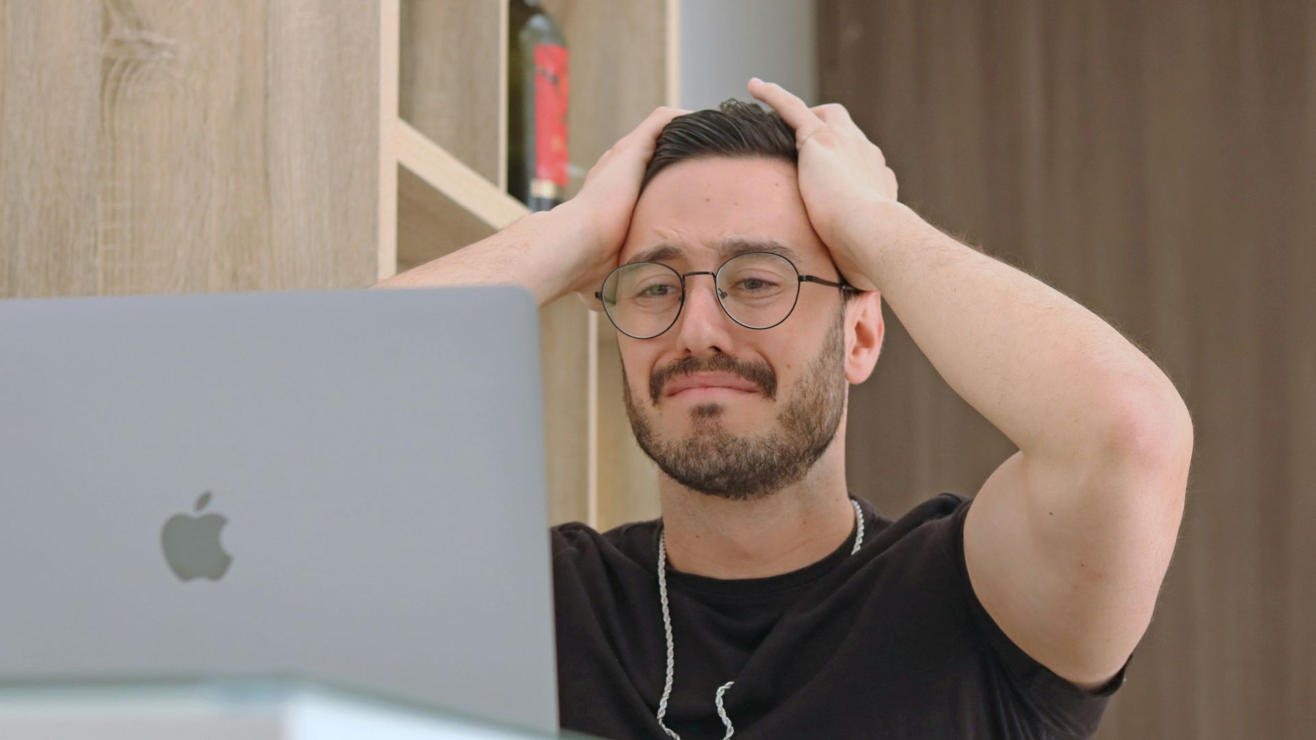 a man with glasses is looking at a laptop