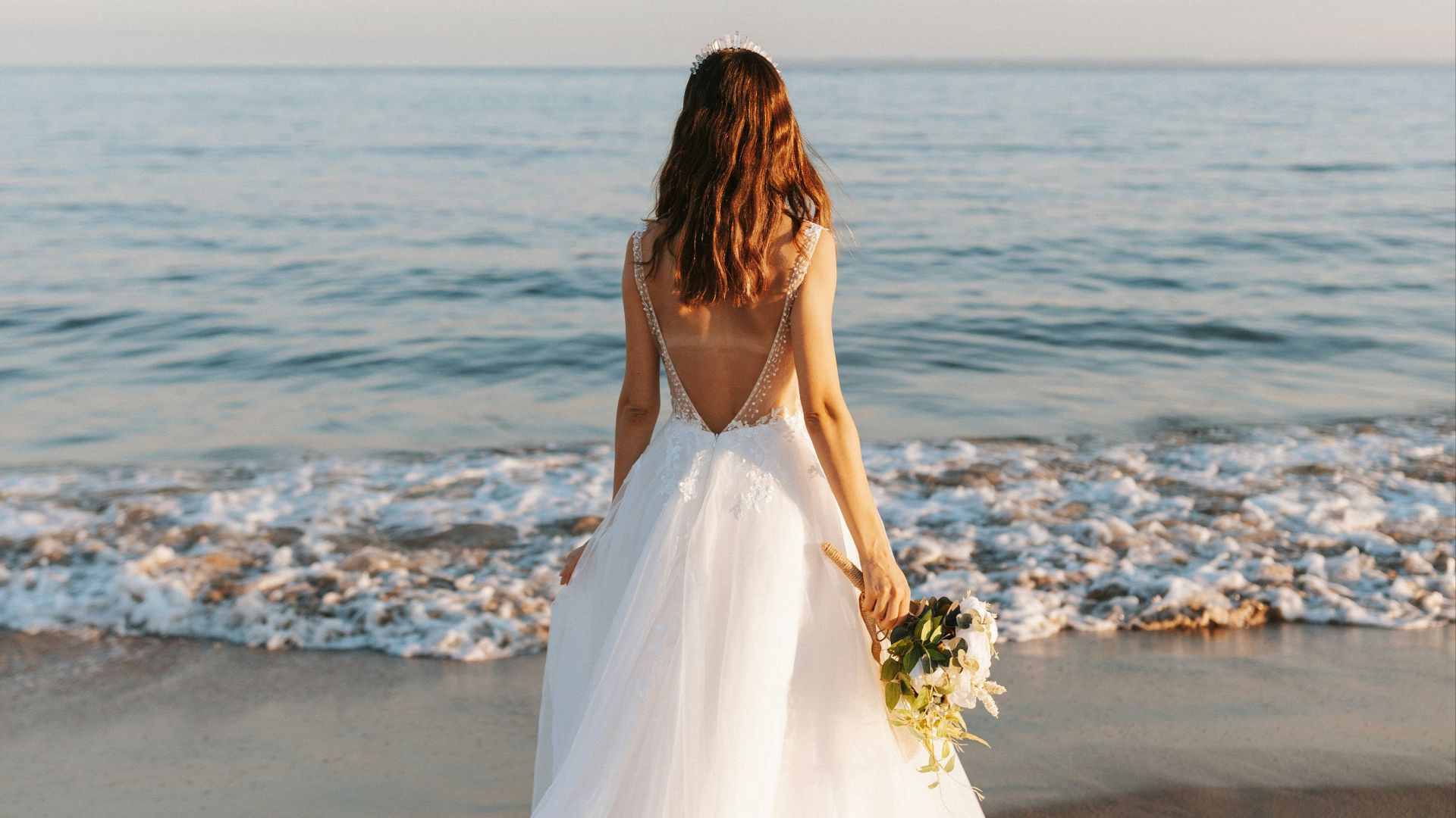 woman in white wedding dress standing on beach during daytime