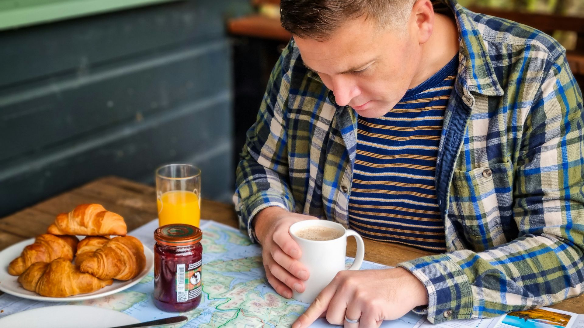 a man sitting at a table with a plate of food and a cup of coffee