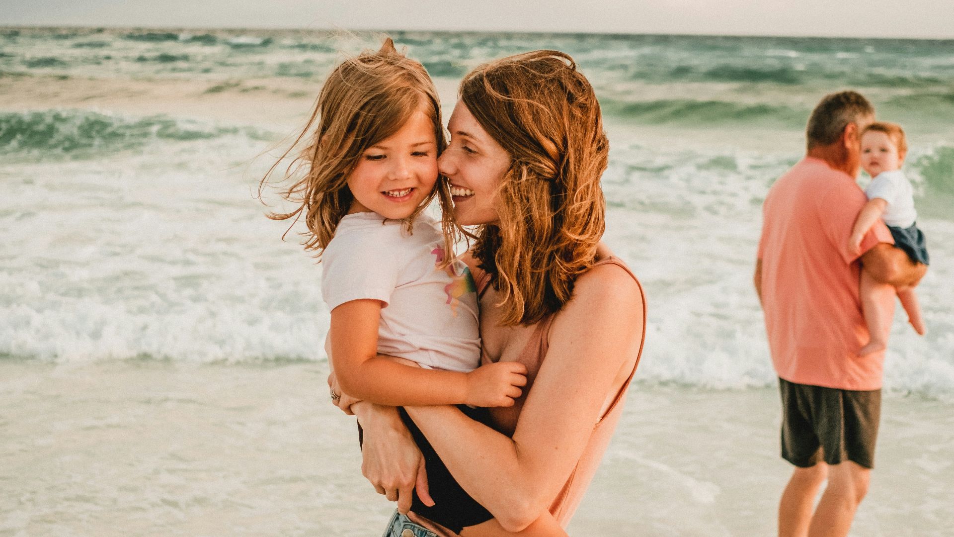 a person holding a baby on a beach