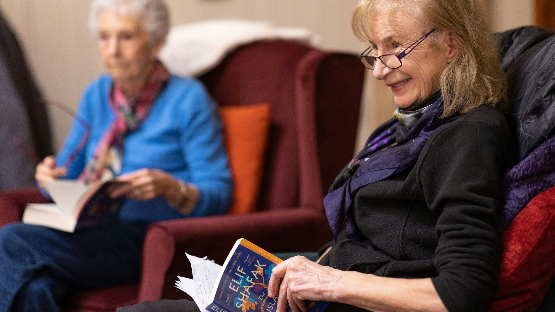 a woman sitting in a chair reading a book