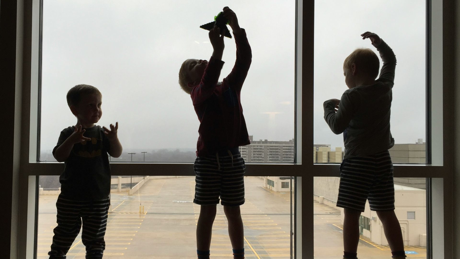 3 boys standing on brown wooden floor during daytime