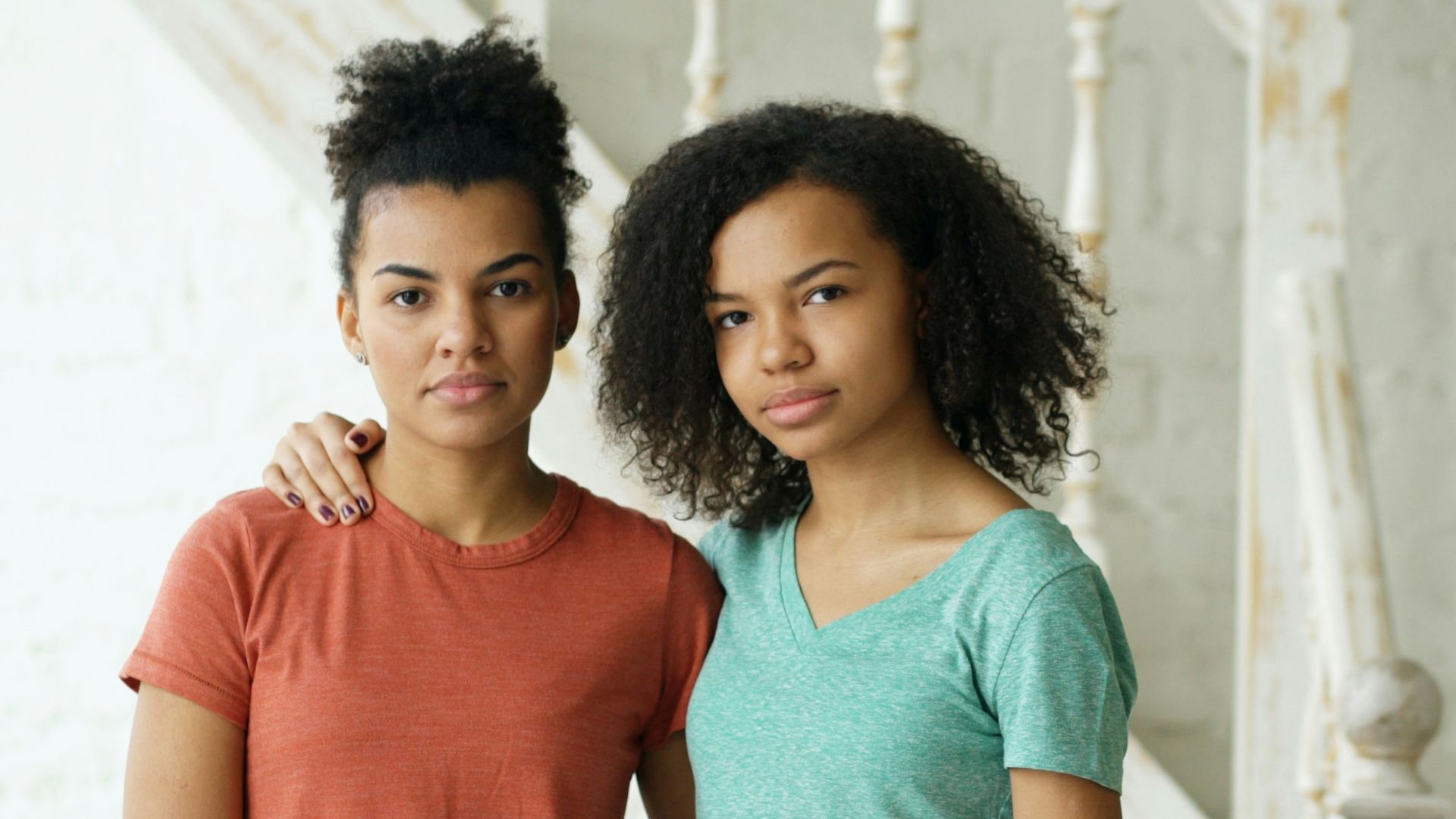 Two young women standing together indoors.