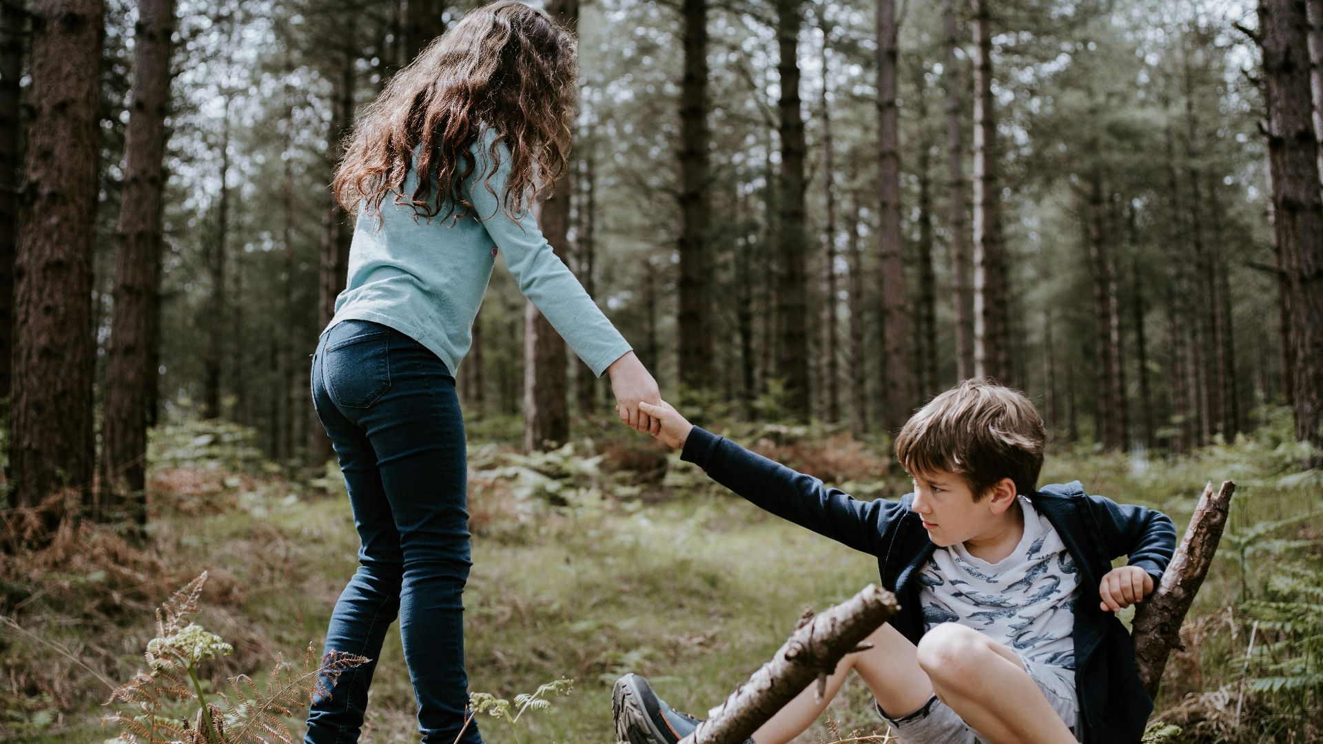 boy and girl playing on three tree log
