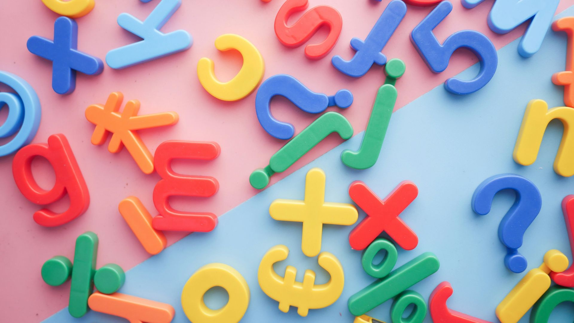 a pile of plastic letters and numbers on a pink and blue background