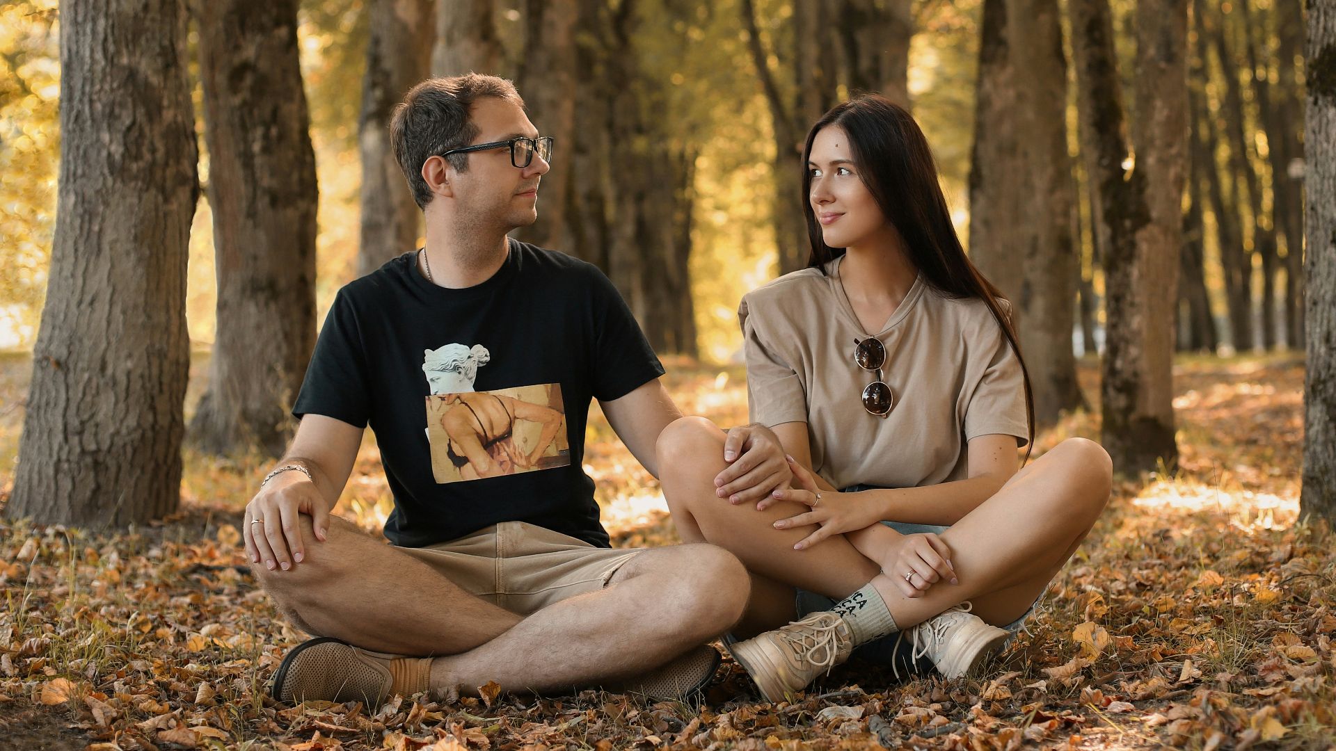 a man and a woman sitting on the ground in a forest