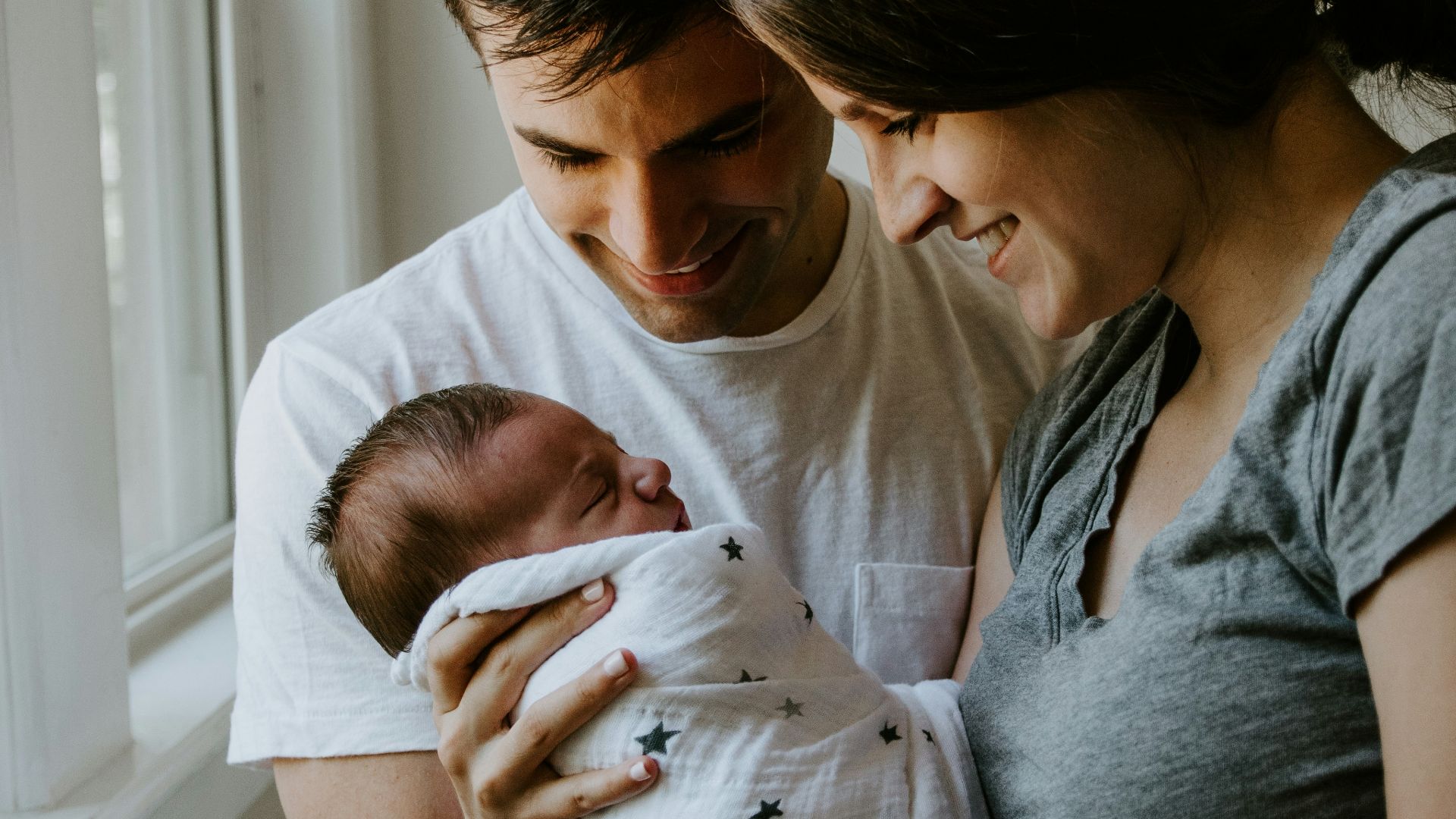 woman holding baby beside man smiling