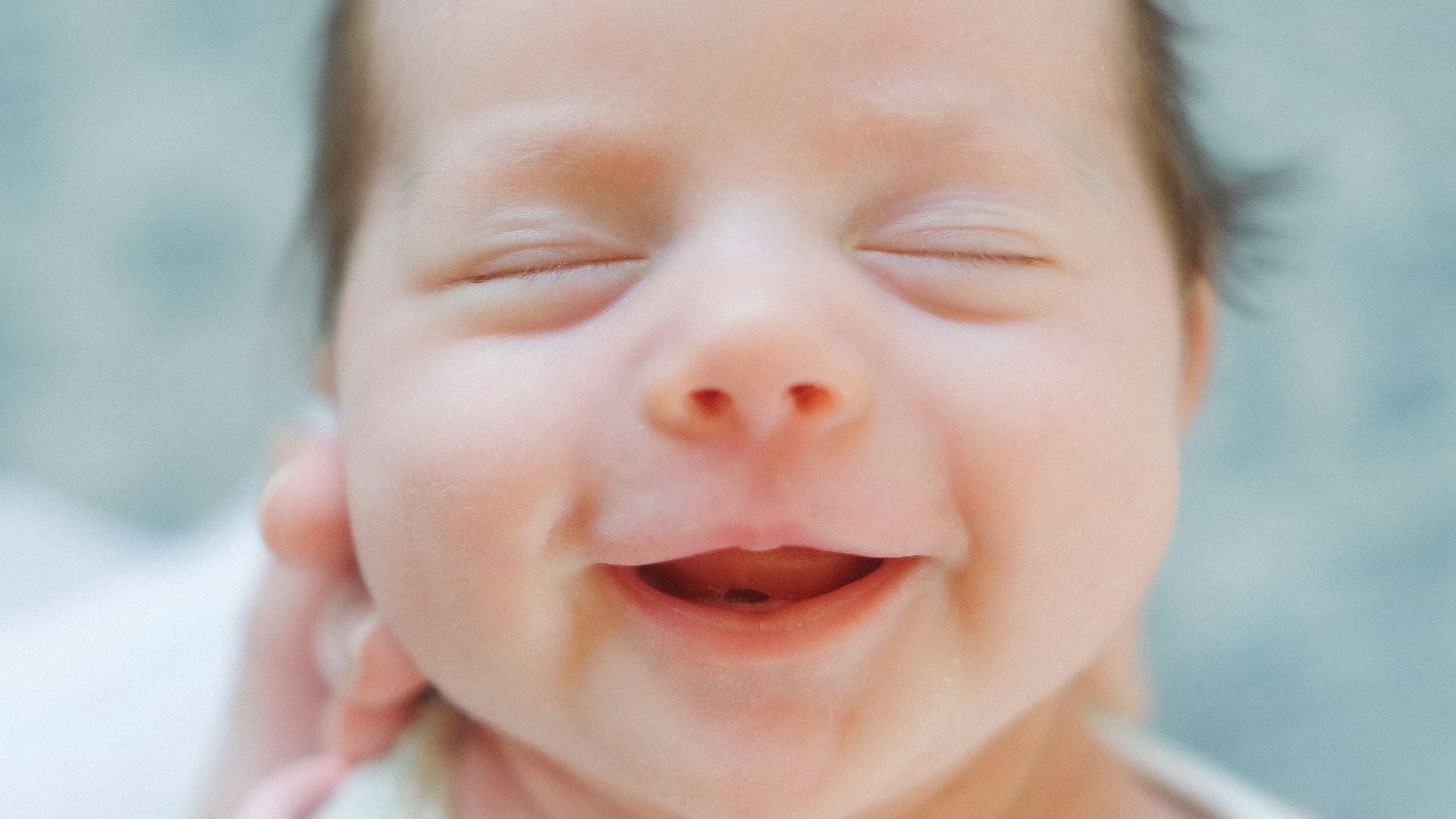 a close up of a baby smiling with its eyes closed