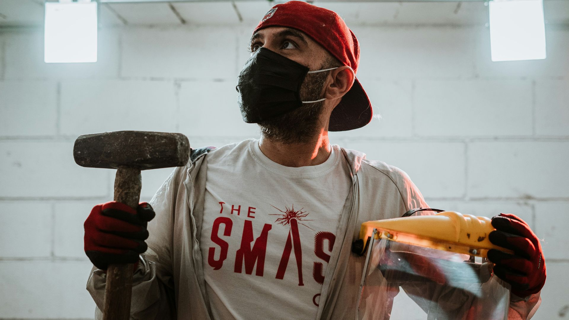 man in white crew neck t-shirt holding brown and black hammer