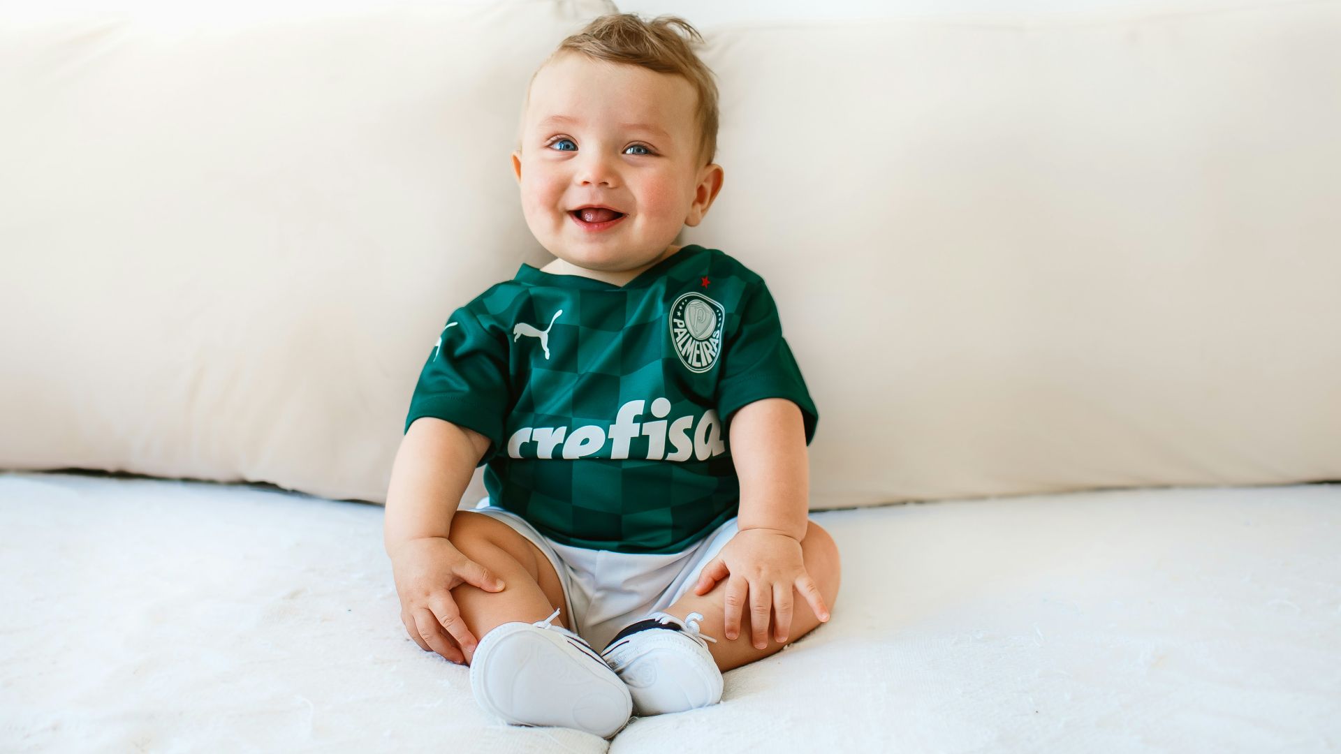 boy in green and white crew neck t-shirt sitting on white bed
