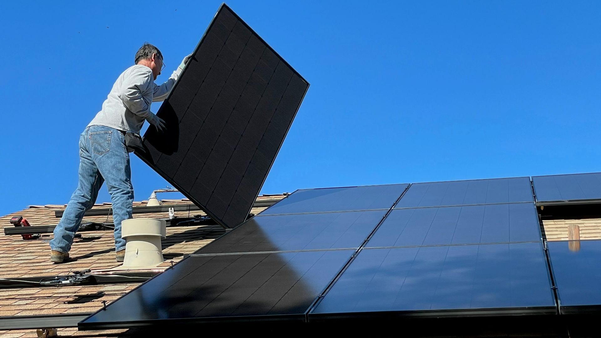 man in white dress shirt and blue denim jeans sitting on white and black solar panel