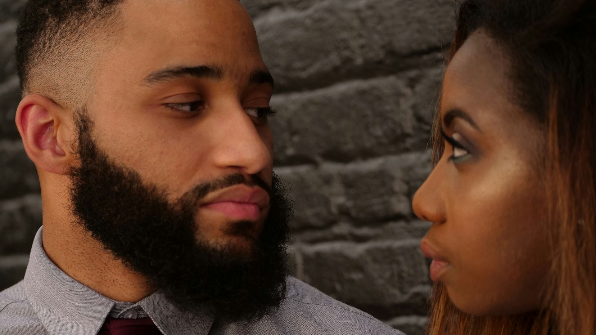 man staring at woman near gray concrete wall