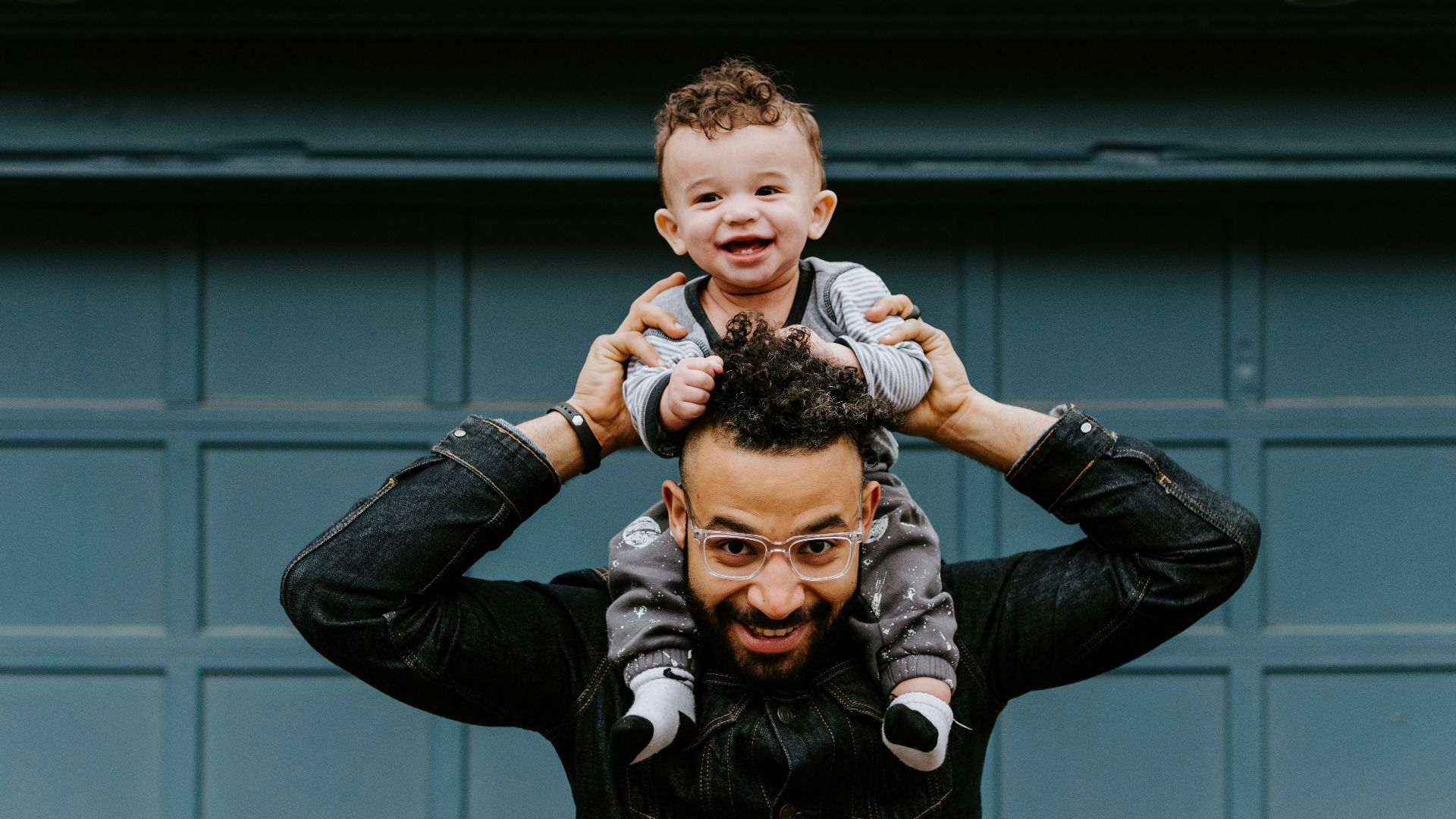 man in black leather jacket carrying boy in black leather jacket