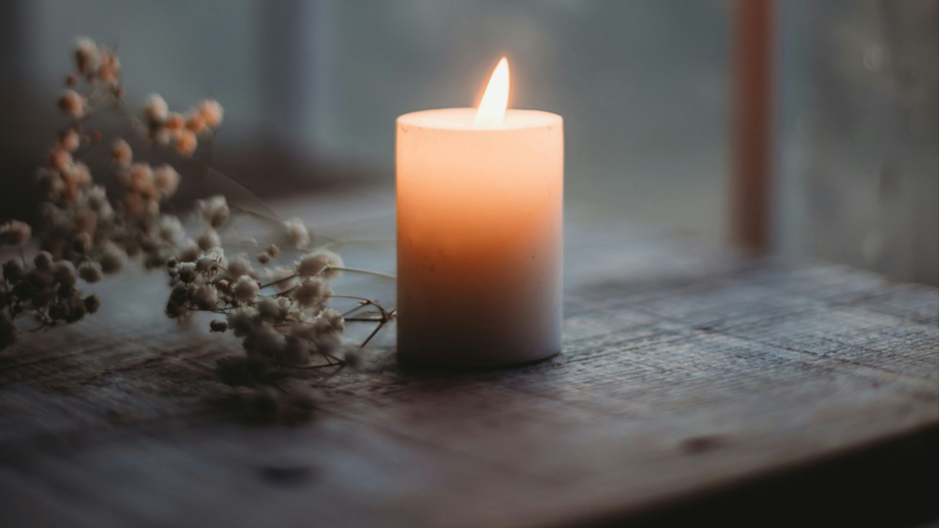 a lit candle sitting on top of a wooden table