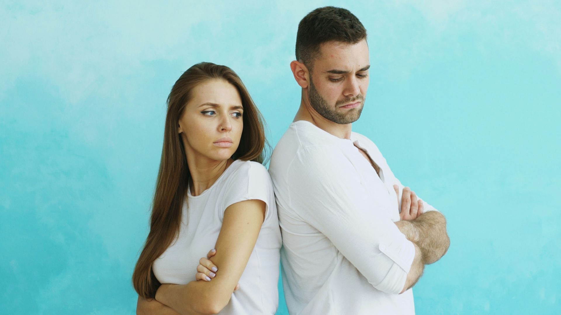 Couple standing back to back with arms crossed