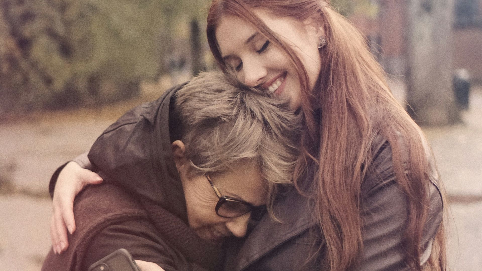 two women hugging each other on a city street