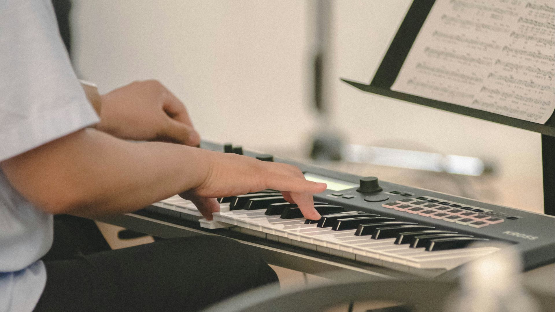 Person playing a digital piano with sheet music.