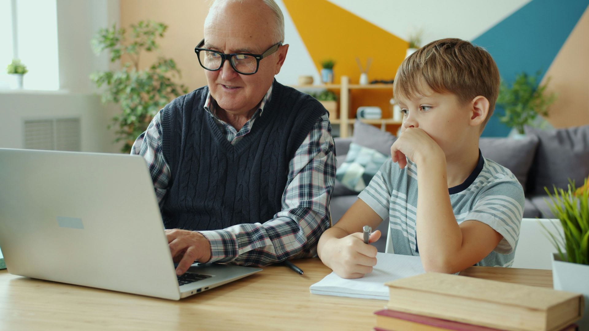 Grandfather and grandson using laptop together at home.