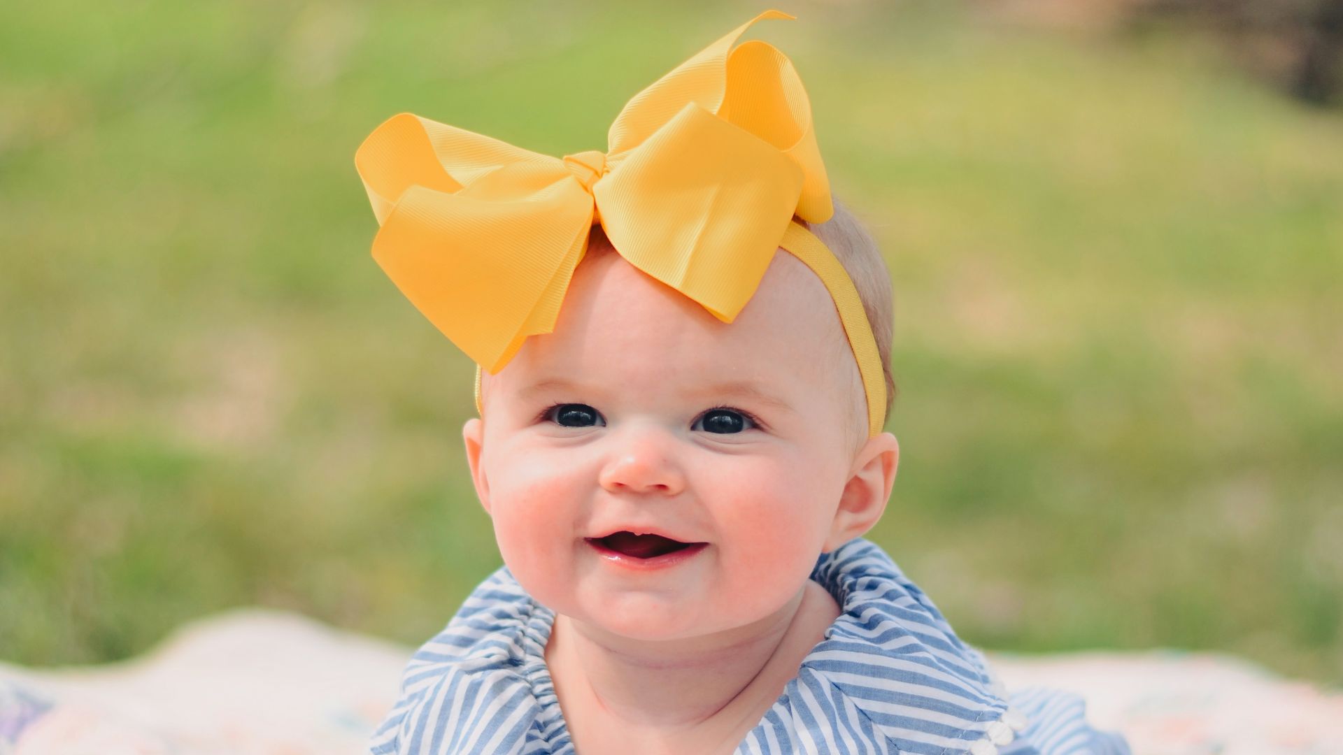smiling baby lying forward on pink textile