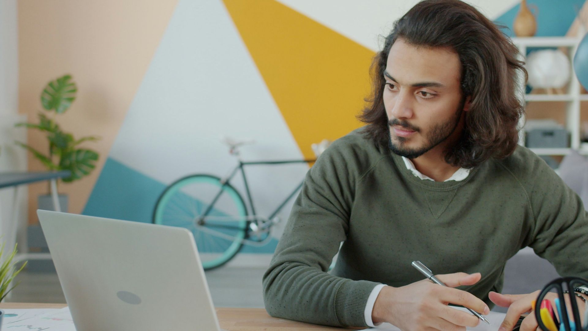 Man working at a desk with a laptop and notebook.
