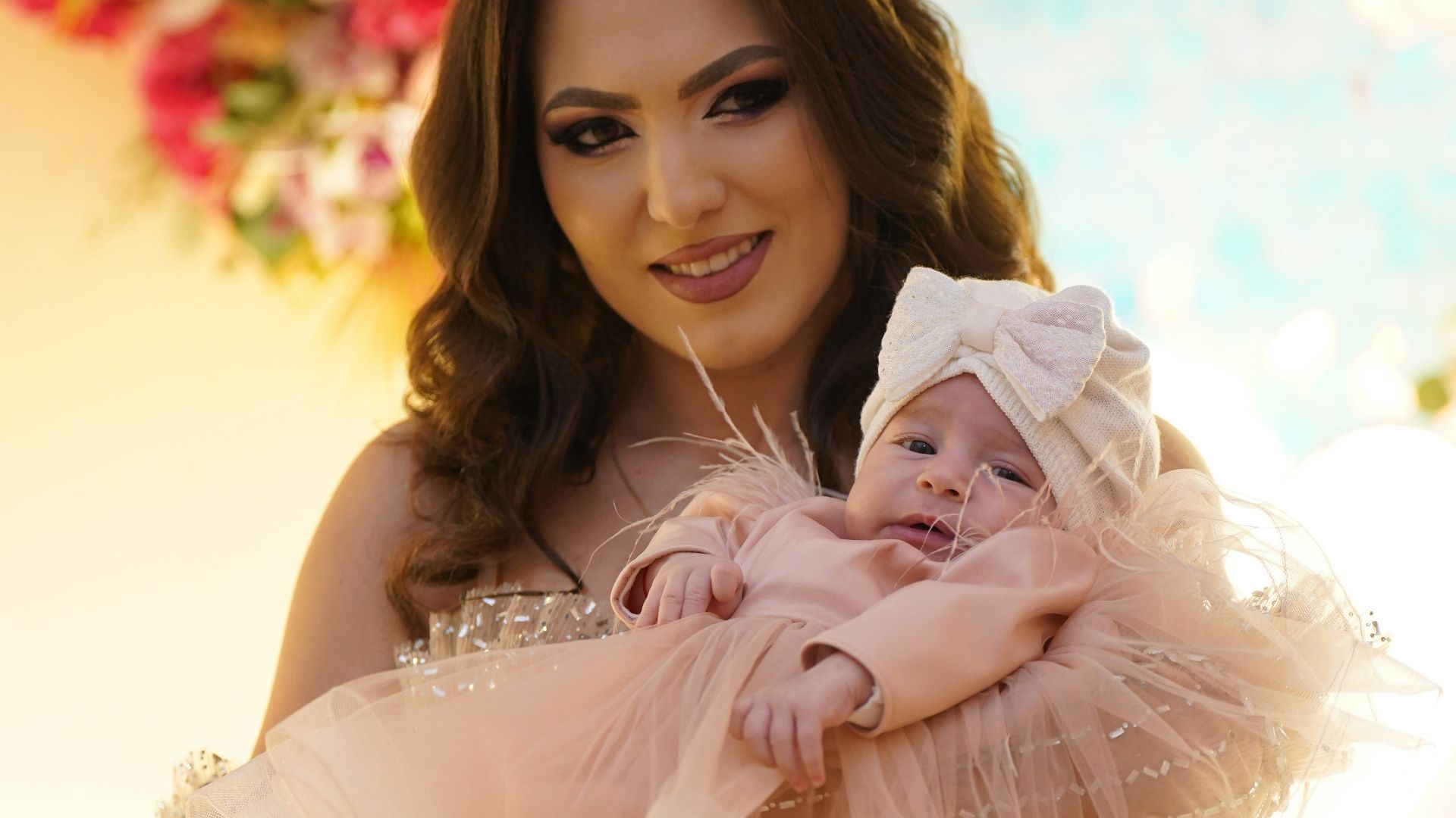 Mother holding her baby in a festive setting.