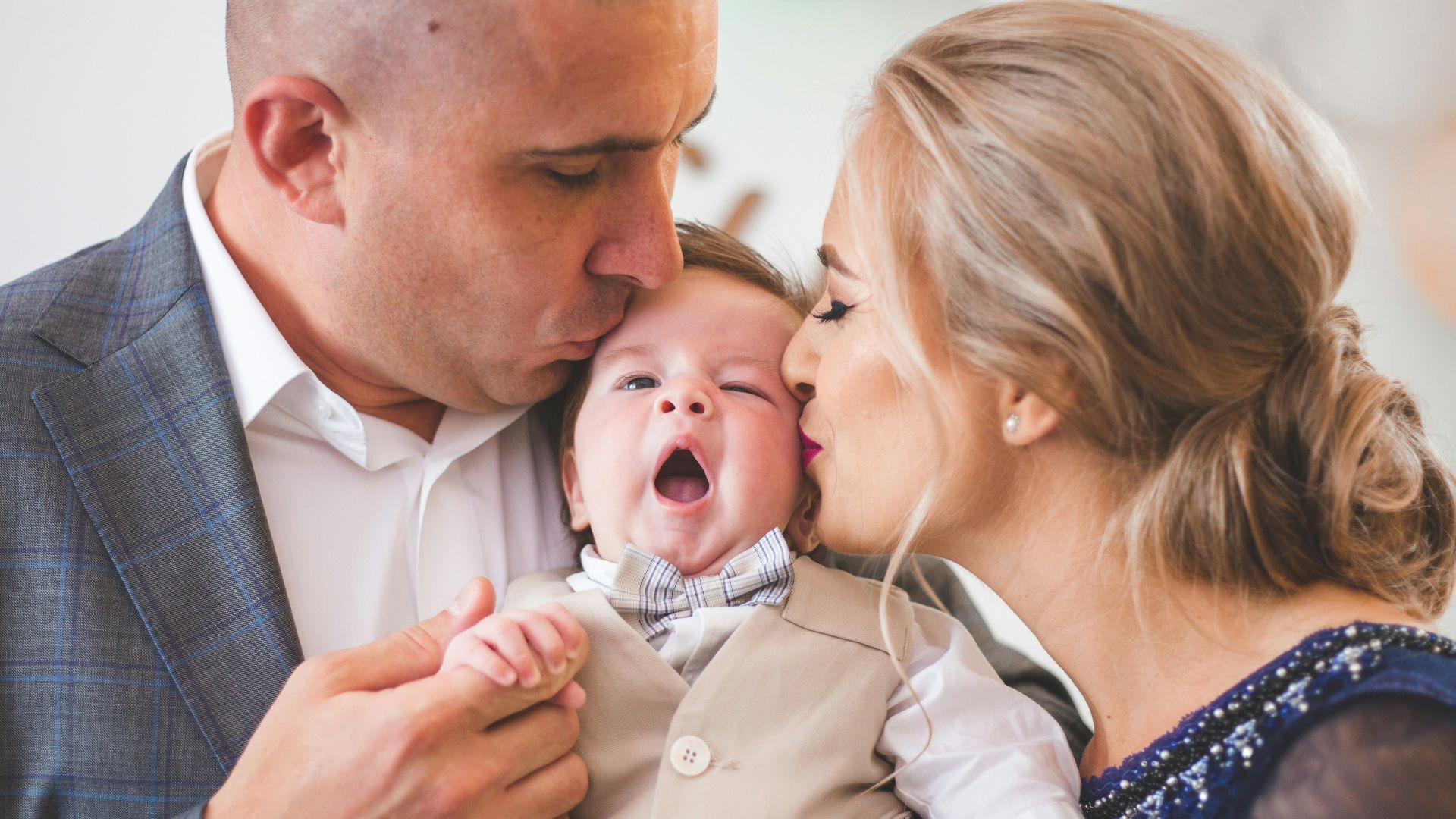 a man and woman holding a baby in front of balloons