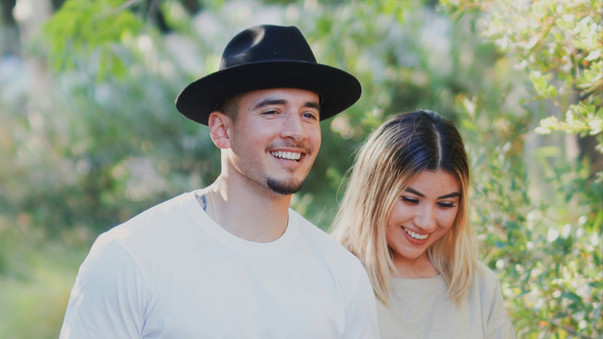 man in white crew neck t-shirt and black pants smiling beside woman in white crew
