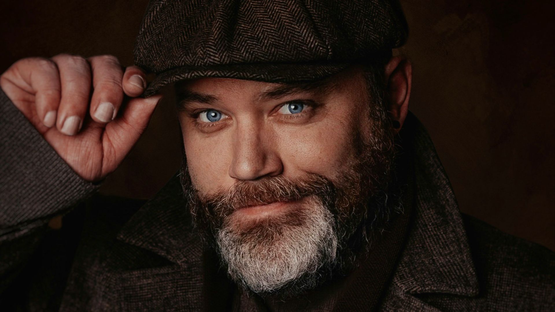 a man with a beard wearing a hat and holding a pipe