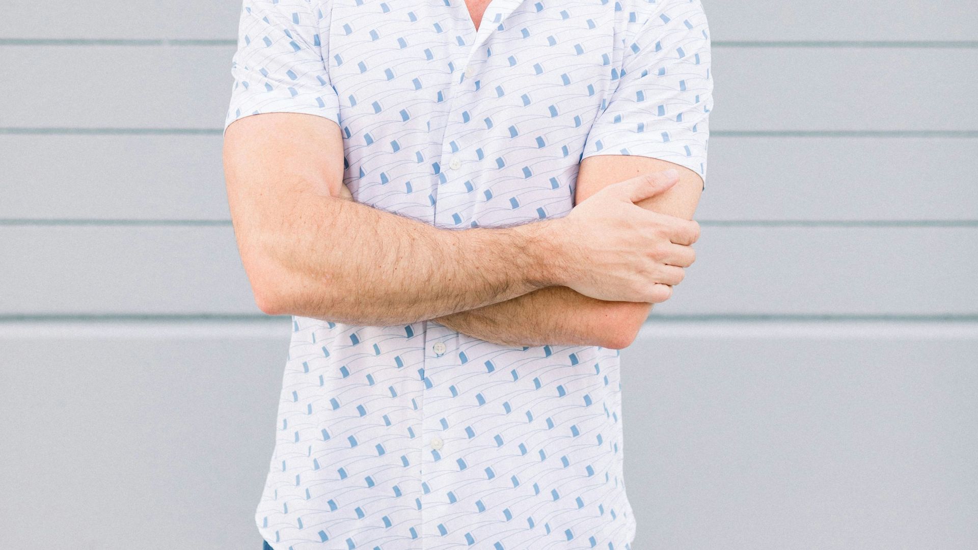 a man standing with his arms crossed in front of a wall