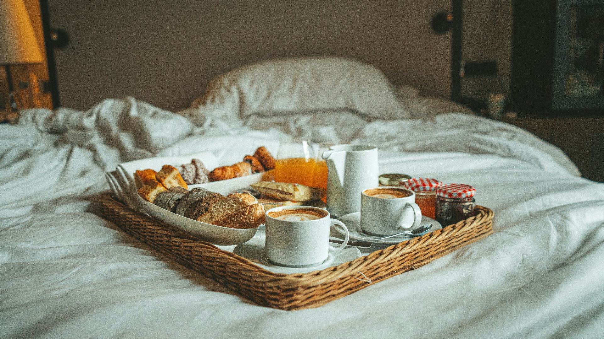 a tray of breakfast on a bed with white sheets