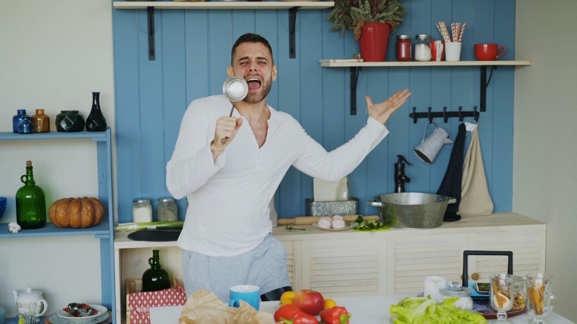 Man singing in kitchen with ladle like a microphone