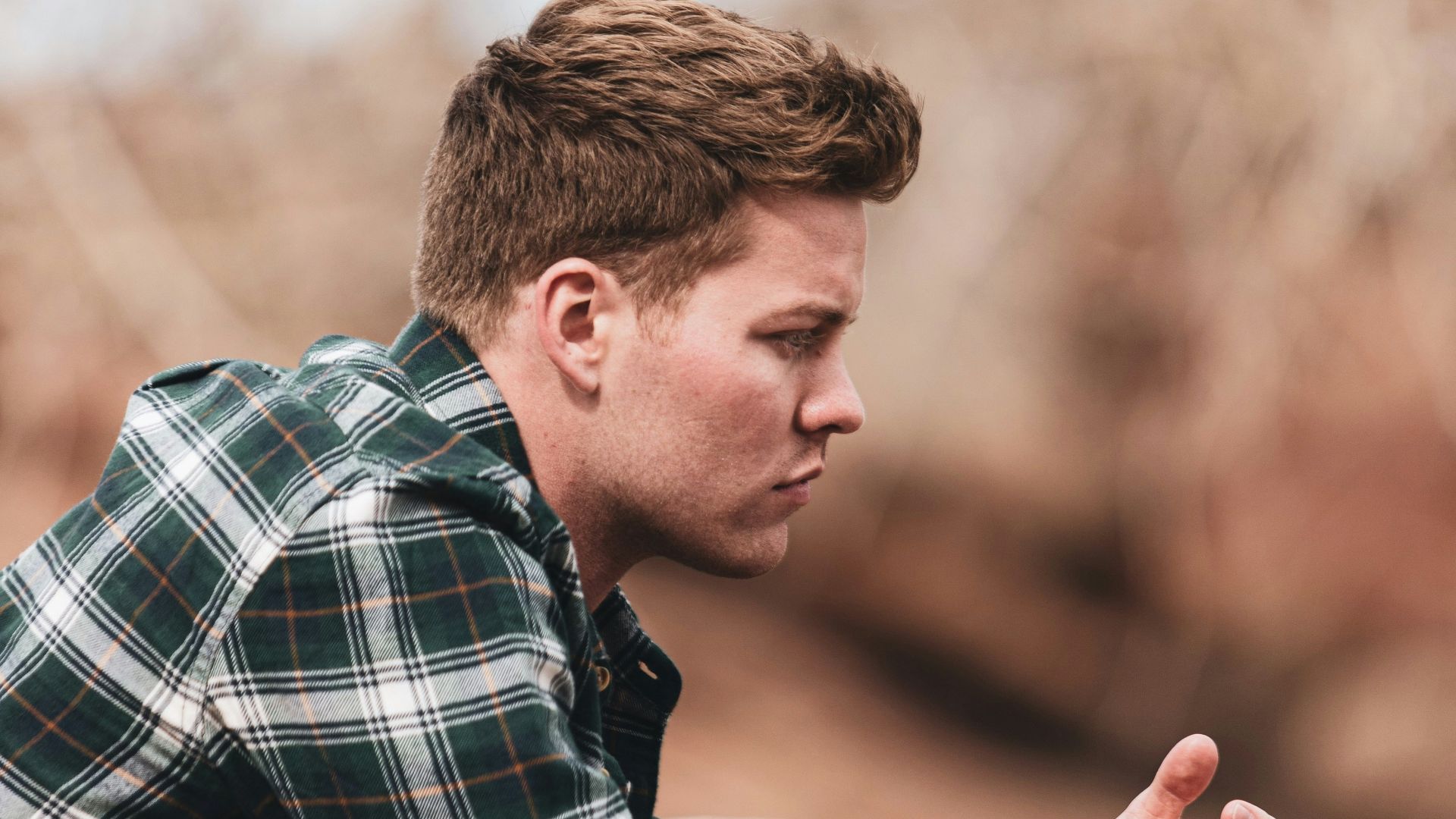 man in black white and gray plaid dress shirt holding smartphone