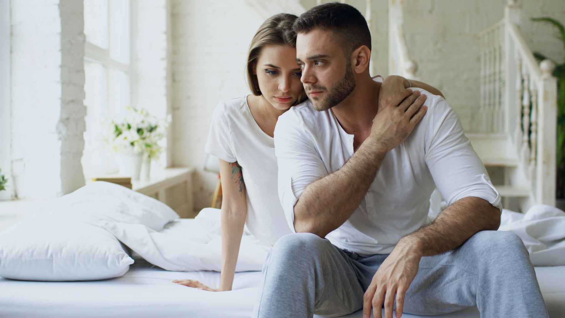 Couple sitting on a bed in a bright room