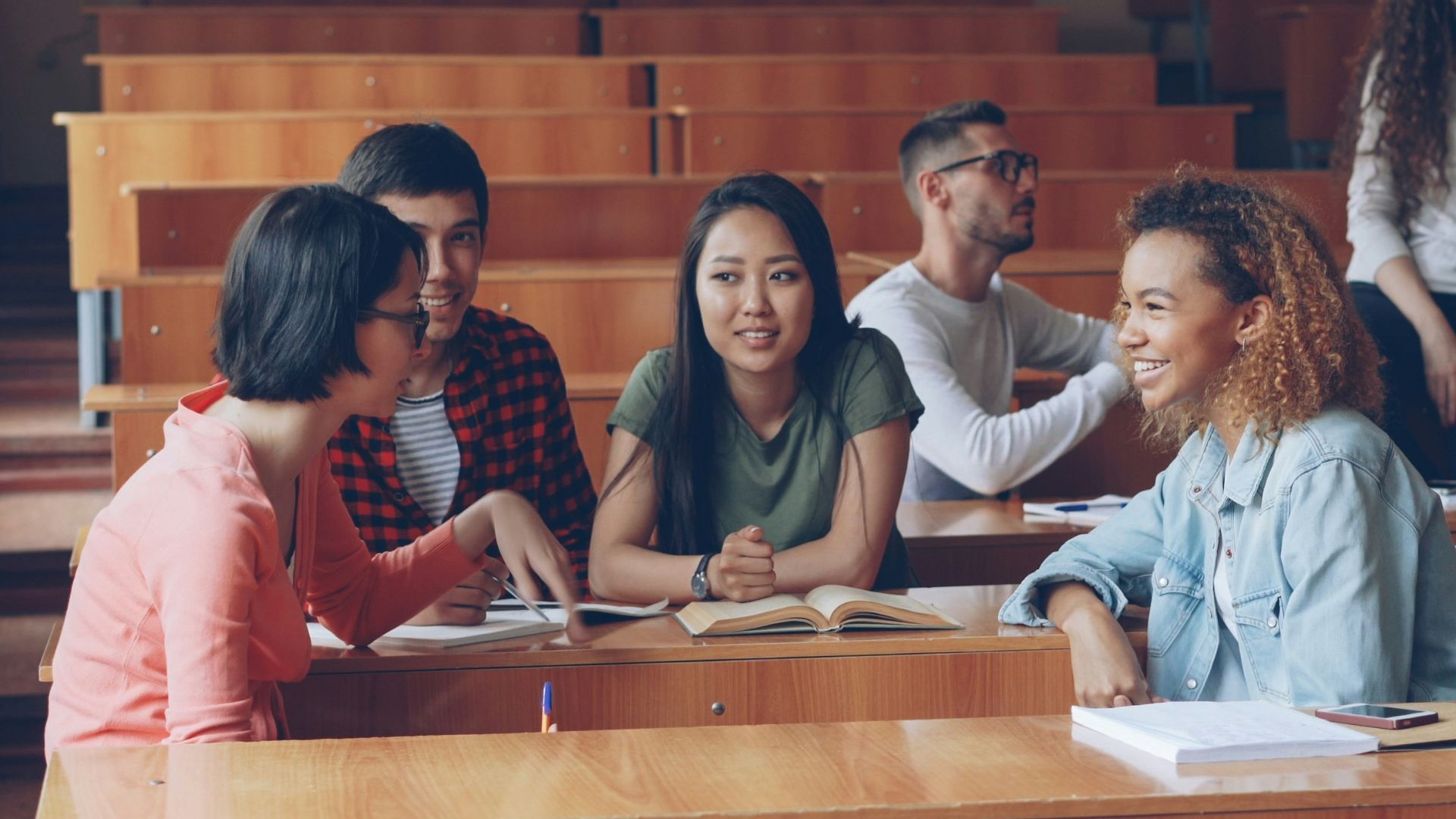 Students talking and studying in a lecture hall.