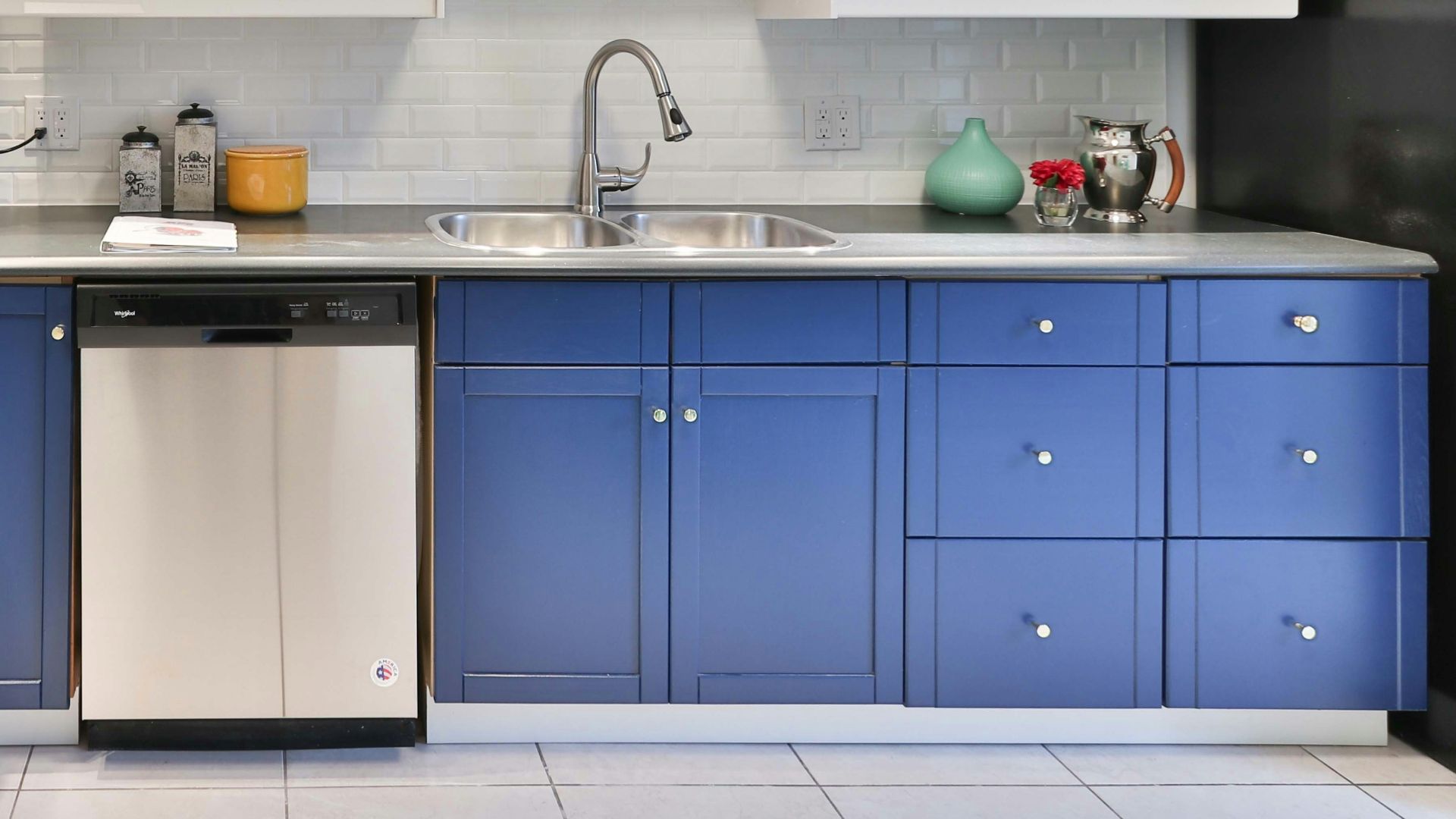 a kitchen with blue cabinets and a black refrigerator