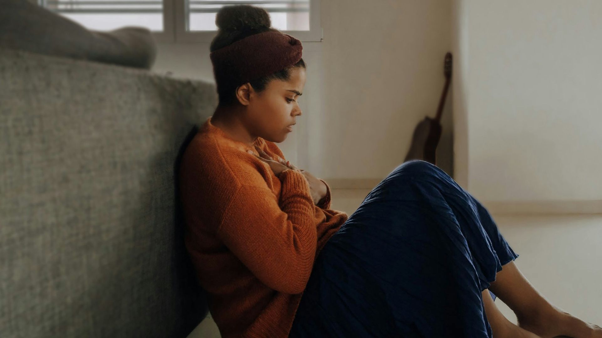 man in orange long sleeve shirt sitting on gray couch