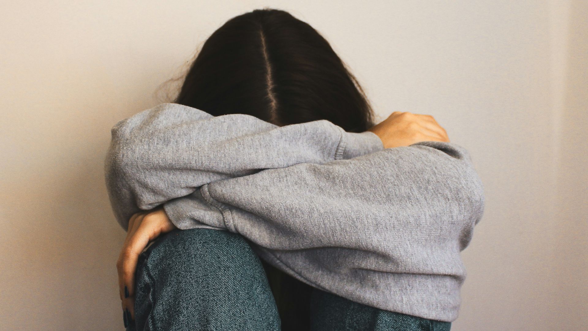 a woman sitting on the floor with her arms wrapped around her head