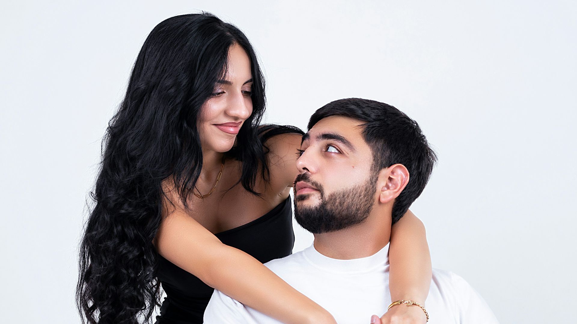 A loving couple poses together in a studio.