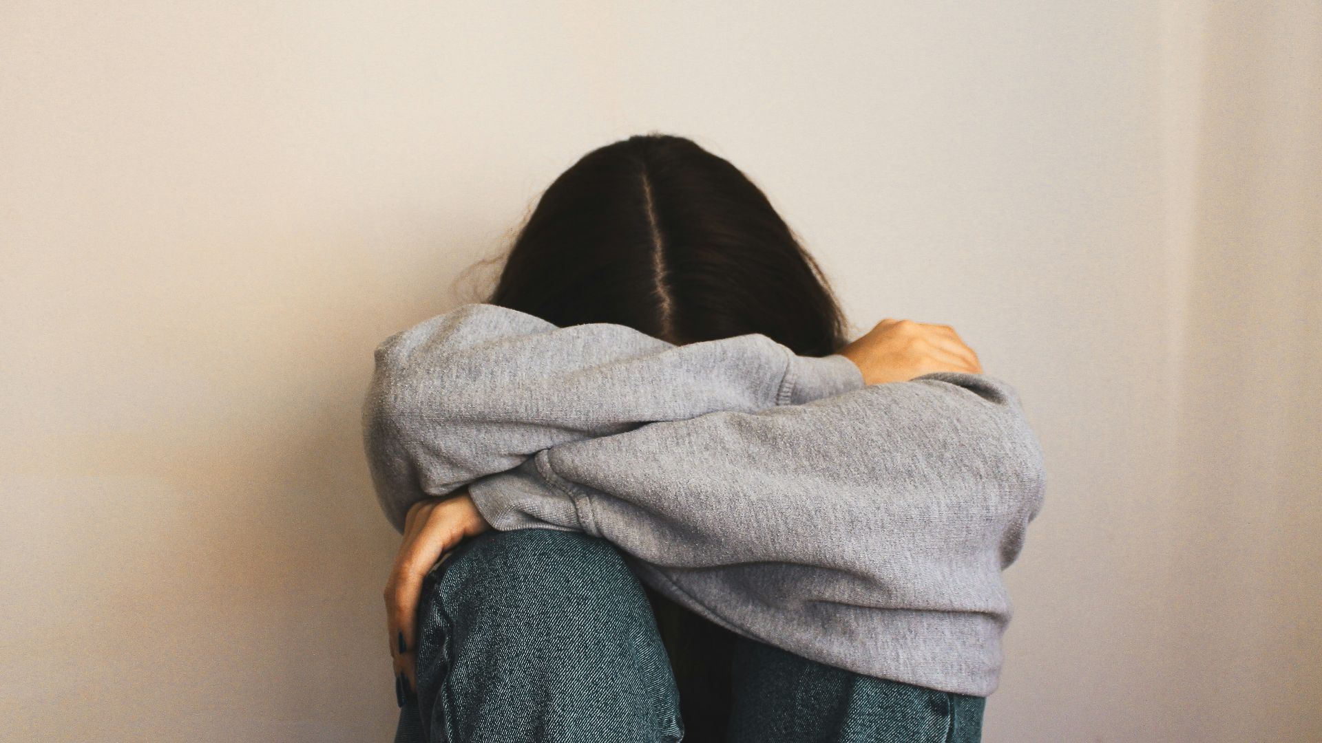 a woman sitting on the floor with her arms wrapped around her head