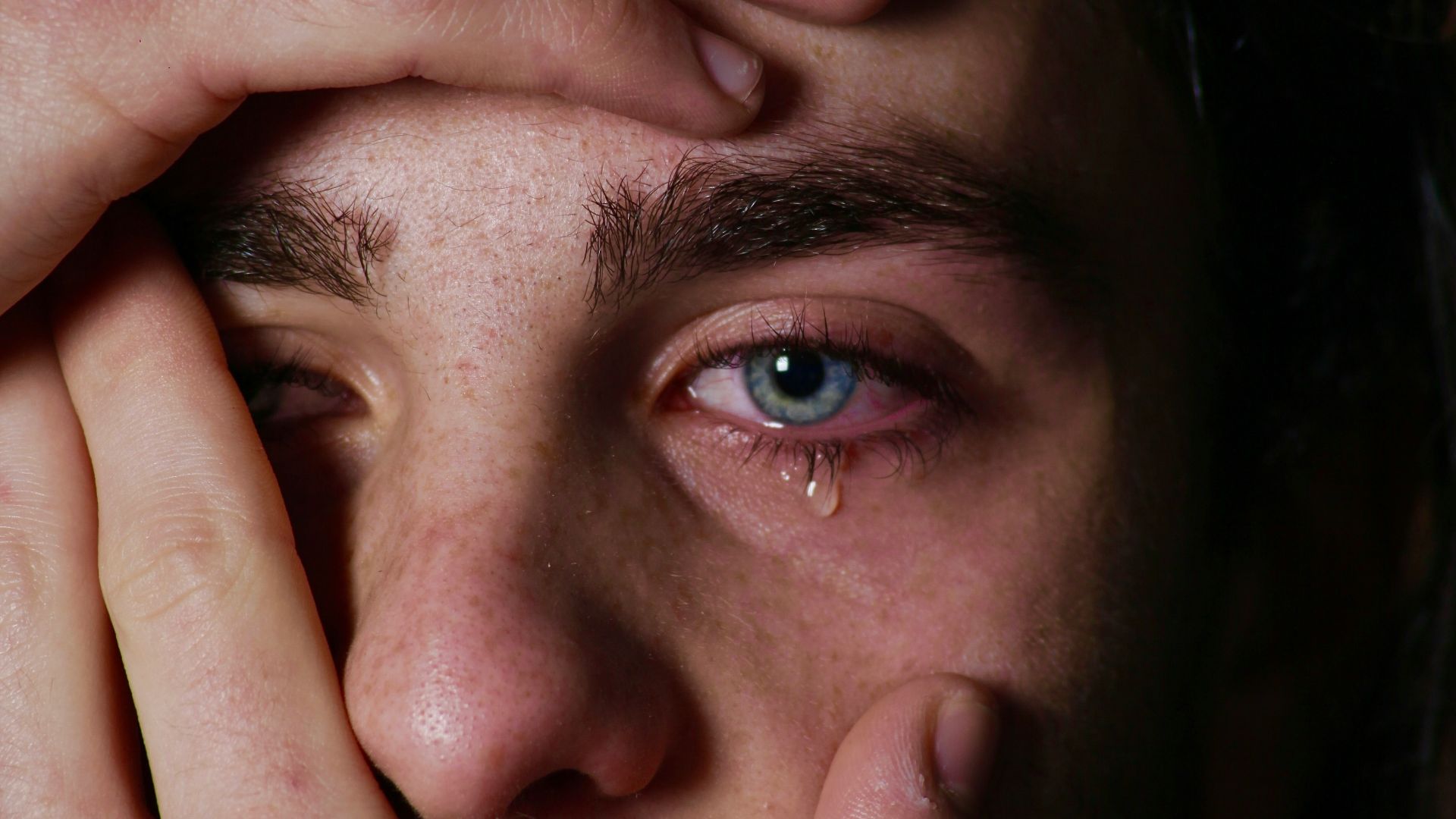 a man holding his hands to his face