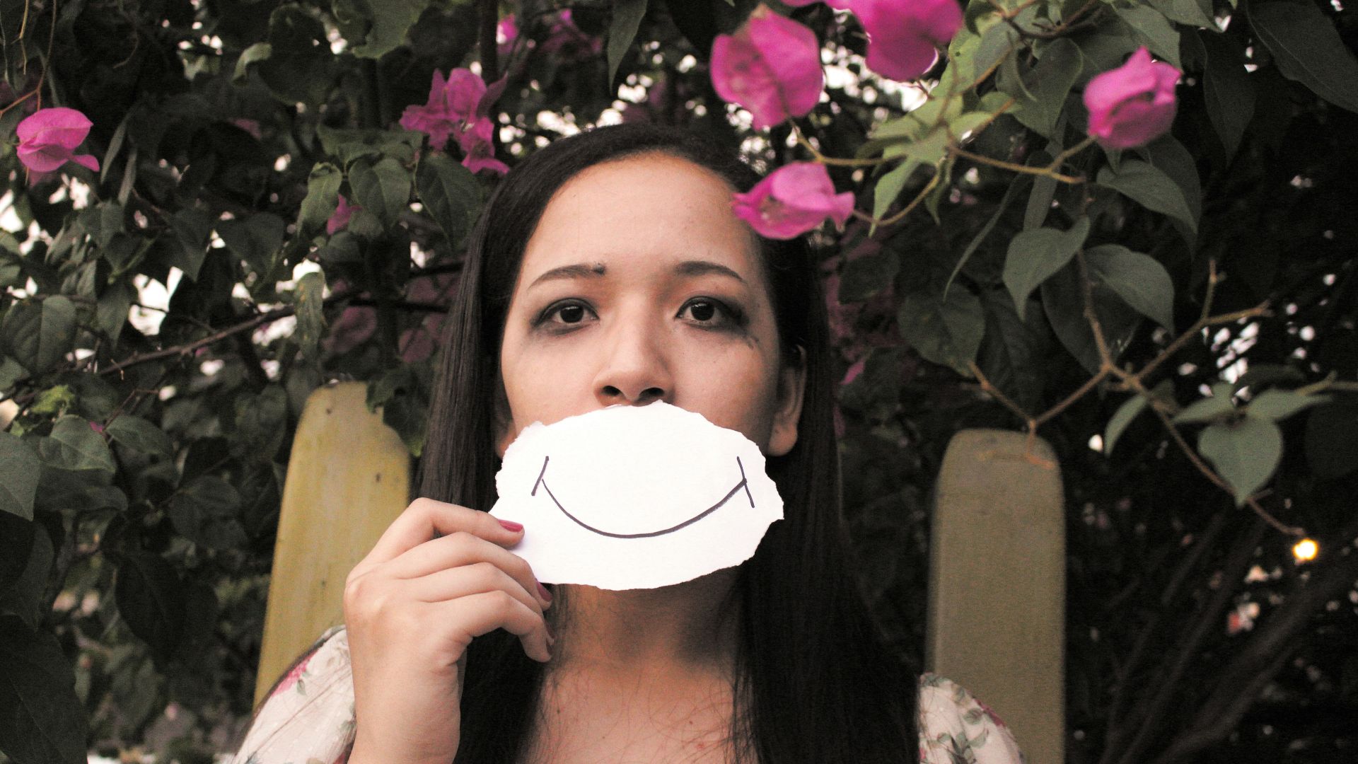 woman standing under pink-petaled flowers