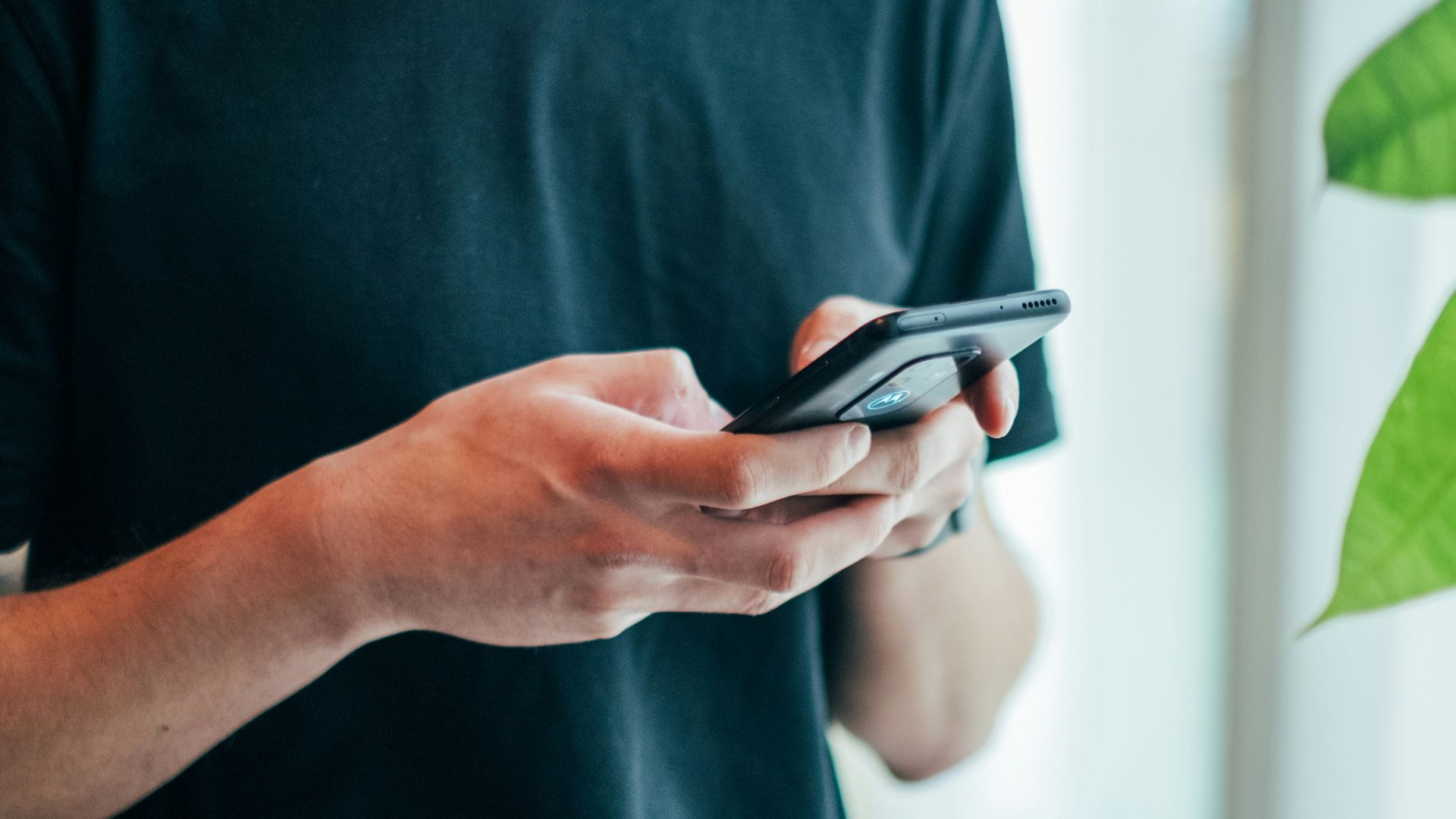 man in black crew-neck top using smartphone