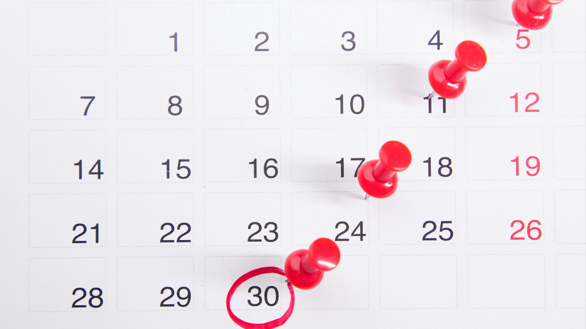 a calendar with red push buttons pinned to it