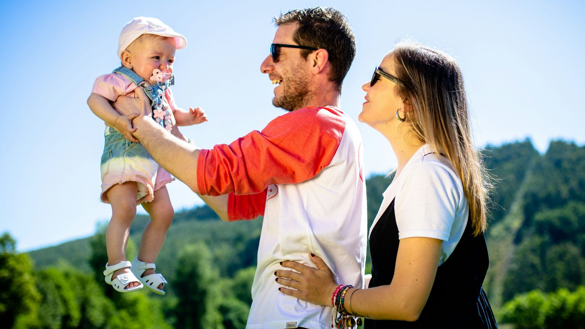 man in white and red polo shirt carrying girl in blue denim jeans during daytime