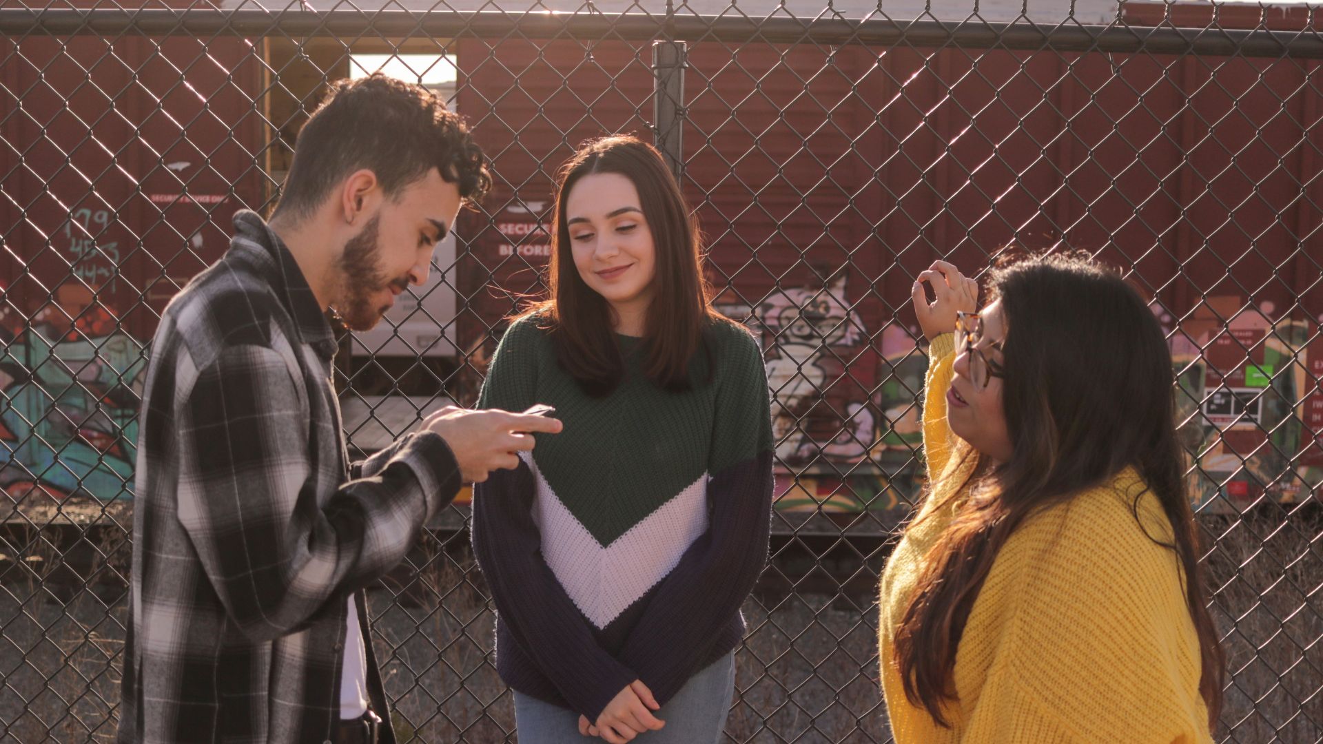 two women and one man standing near fence